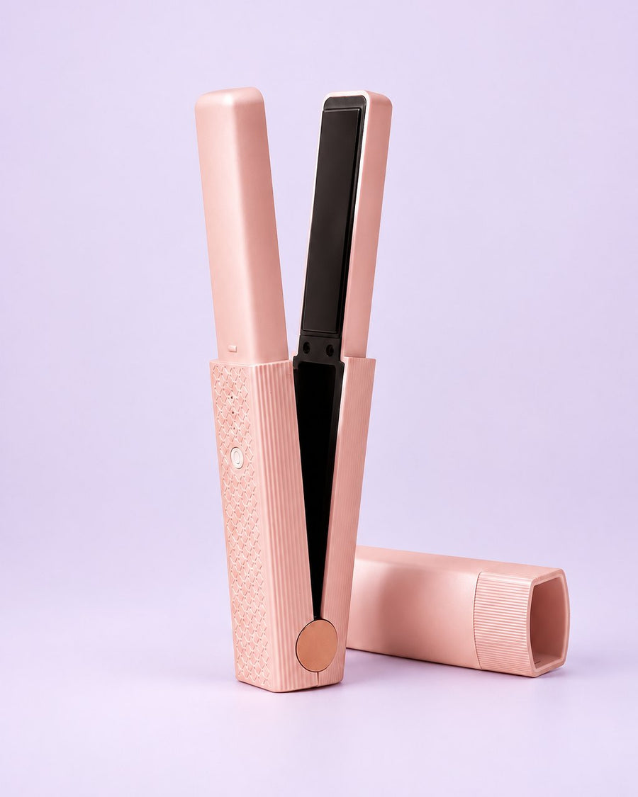 Pink cordless mini flat iron standing open beside its cap