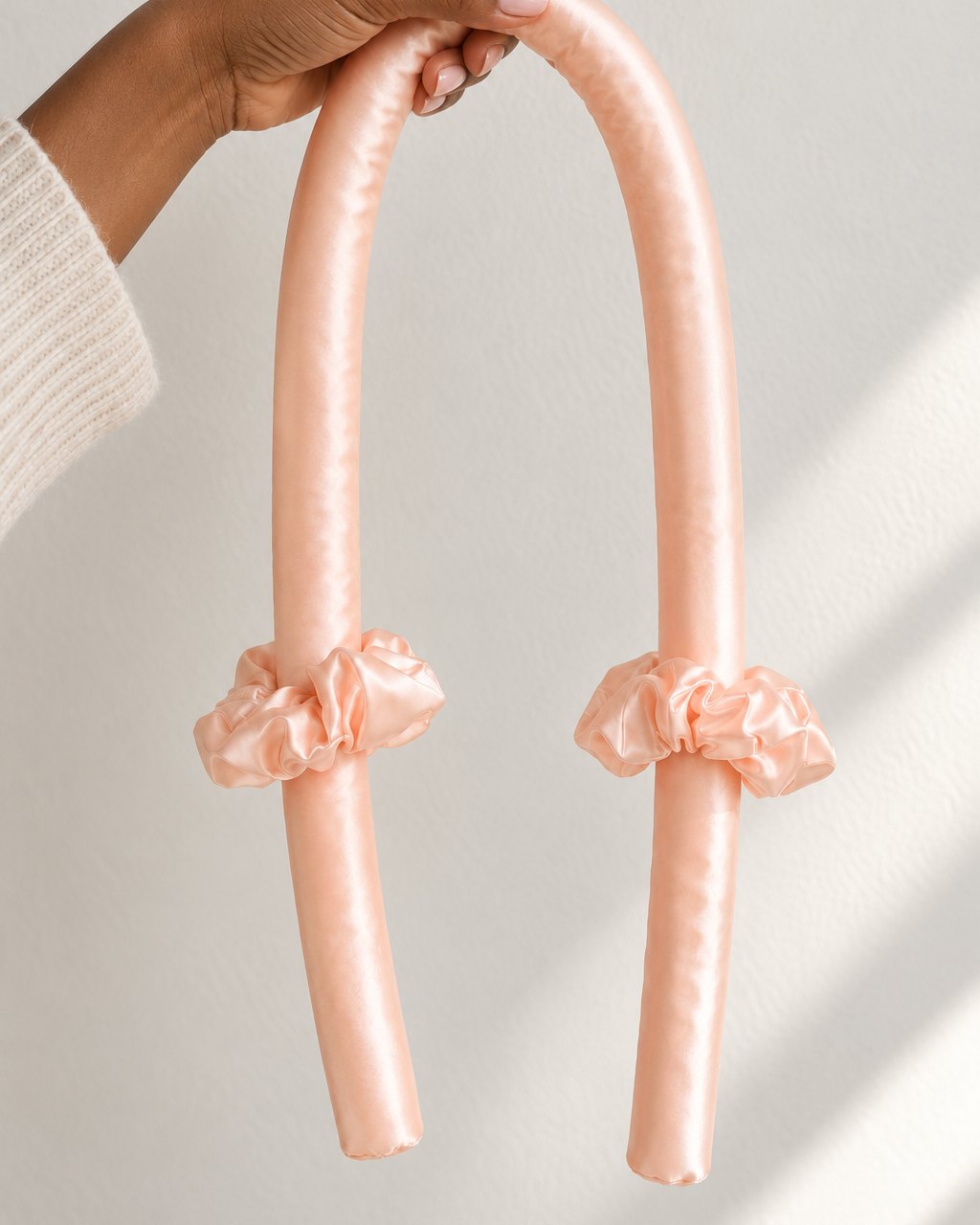 The curling rod draped over a hand, showing its length and soft bend