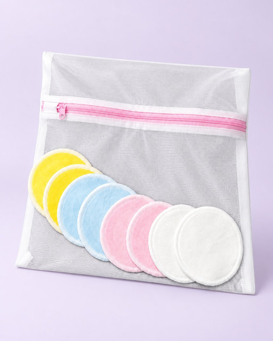 Eight soft reusable face rounds in four pastel colours beside a mesh wash bag