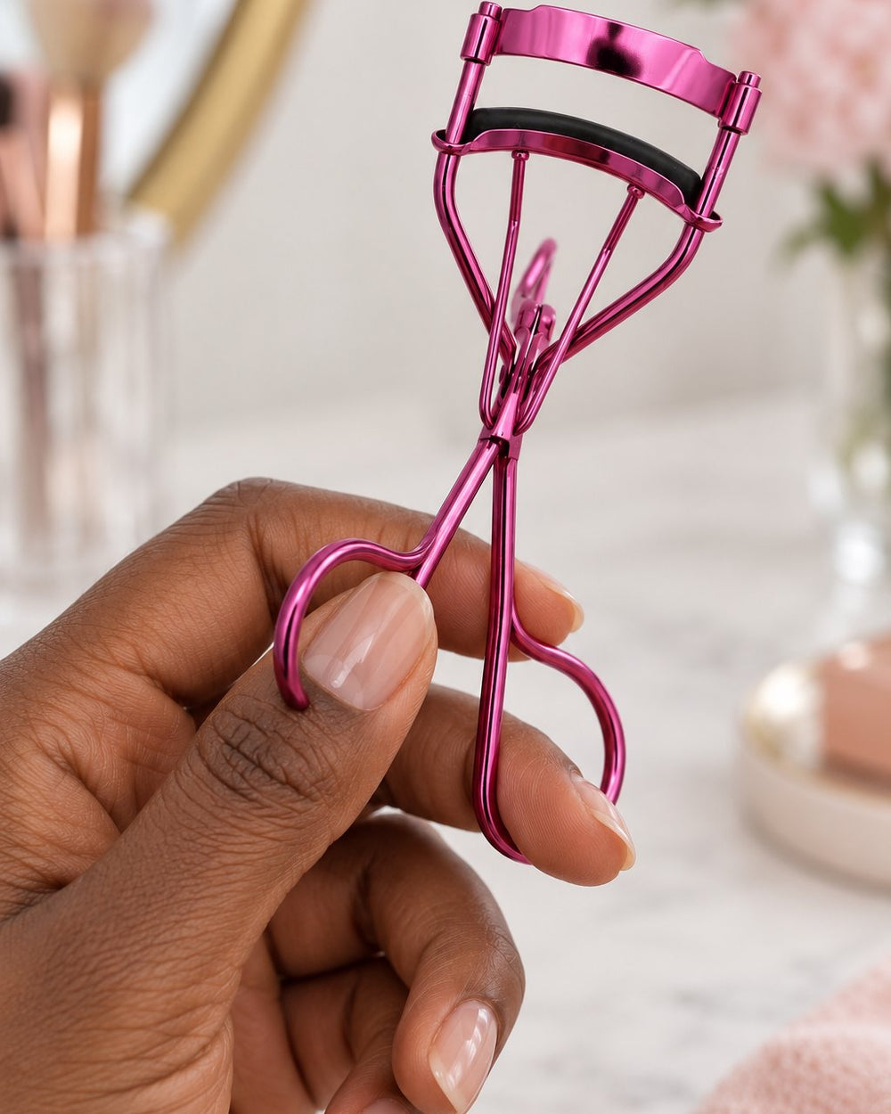 The lash curler held in one hand by its loops