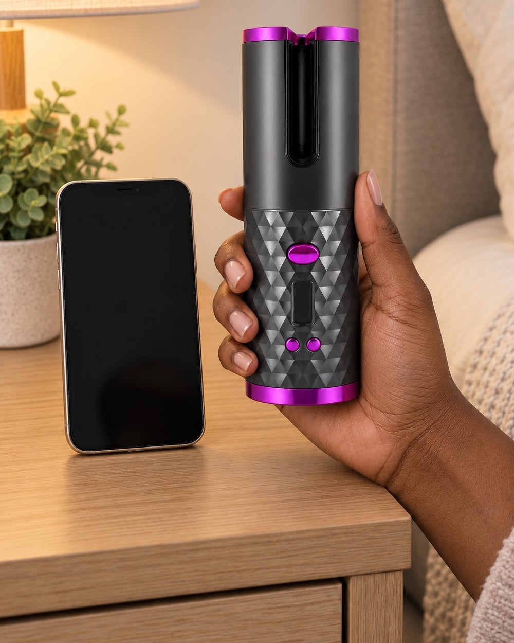The curler held upright in one hand next to a phone