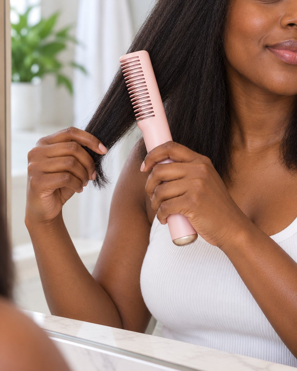 A woman combs the heated comb through the ends of a section of her shoulder-length hair