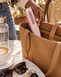 The capped comb going into an open tote bag next to sunglasses and keys