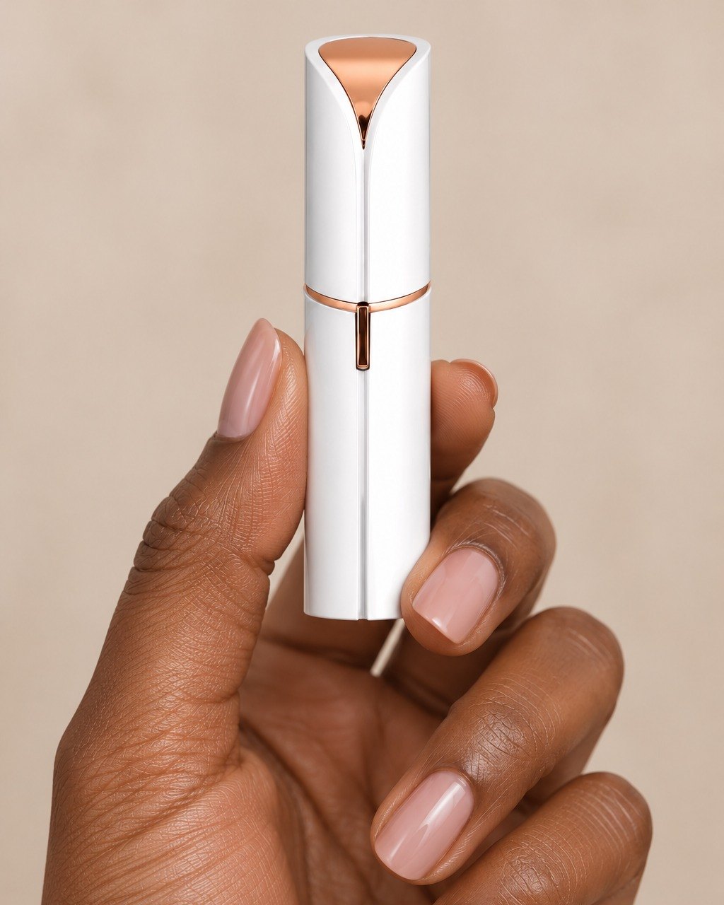 The facial hair remover held between thumb and fingers, the size of a lipstick