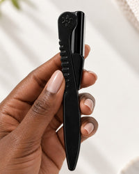 The razor folded flat between two fingers, about the length of a pen