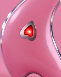 Close-up of the heart button glowing red on the glossy pink gua sha