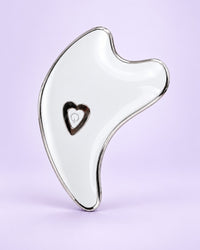 White dolphin-shaped gua sha with a heart light in the middle