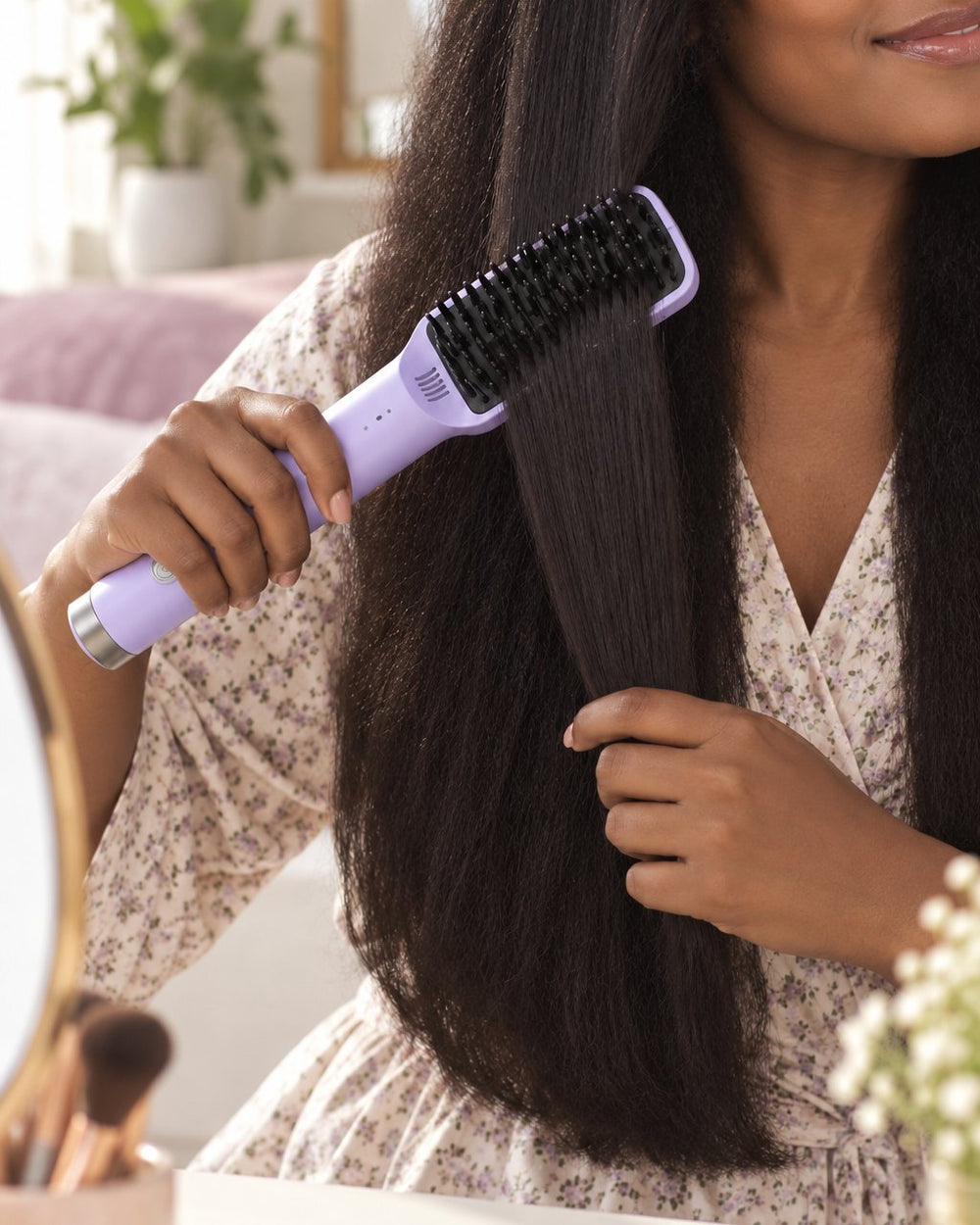 A woman brushes the heated brush down a section of long, thick dark hair