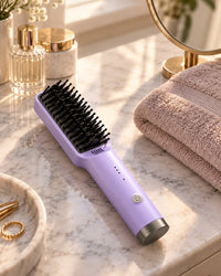 The purple brush on a marble bathroom counter beside a folded towel
