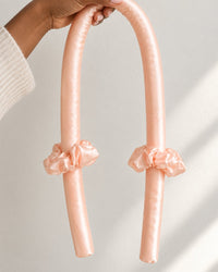 The curling rod draped over a hand, showing its length and soft bend