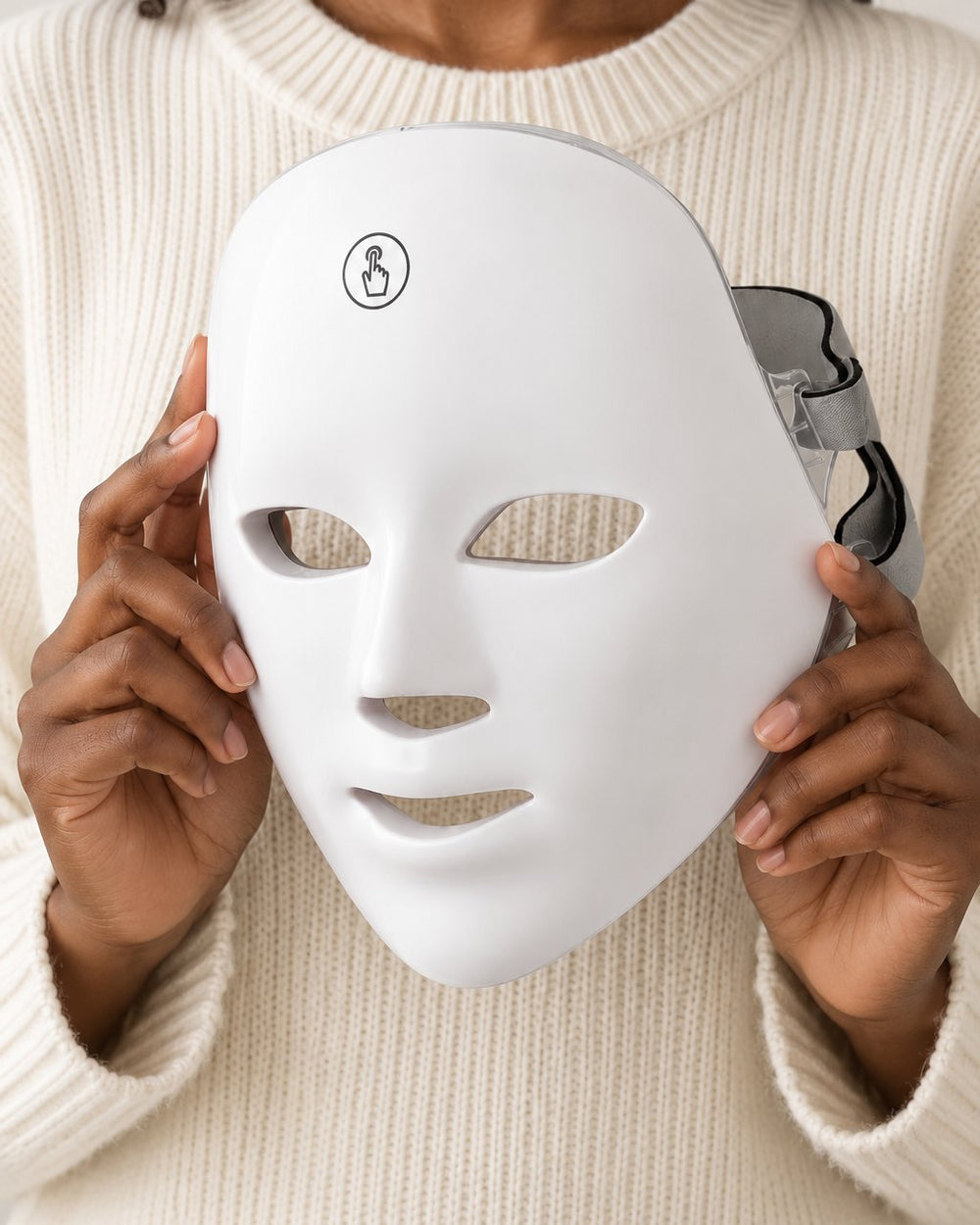 LED face mask held up in two hands, showing it covers a whole adult face