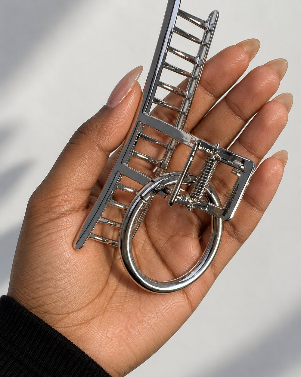 The silver claw clip held between fingers, about the width of a palm