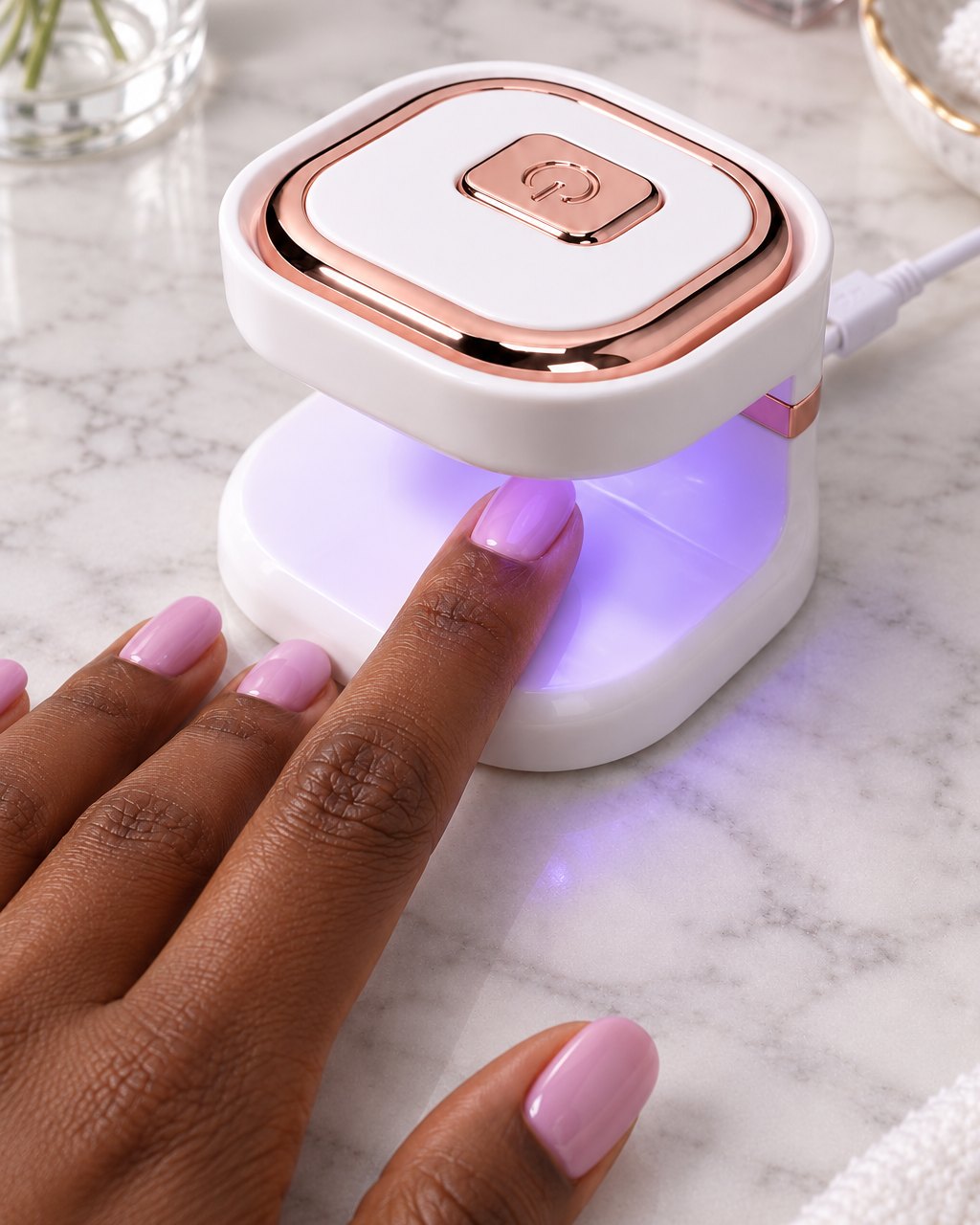 Fingertip with fresh gel polish under the glowing mini nail lamp