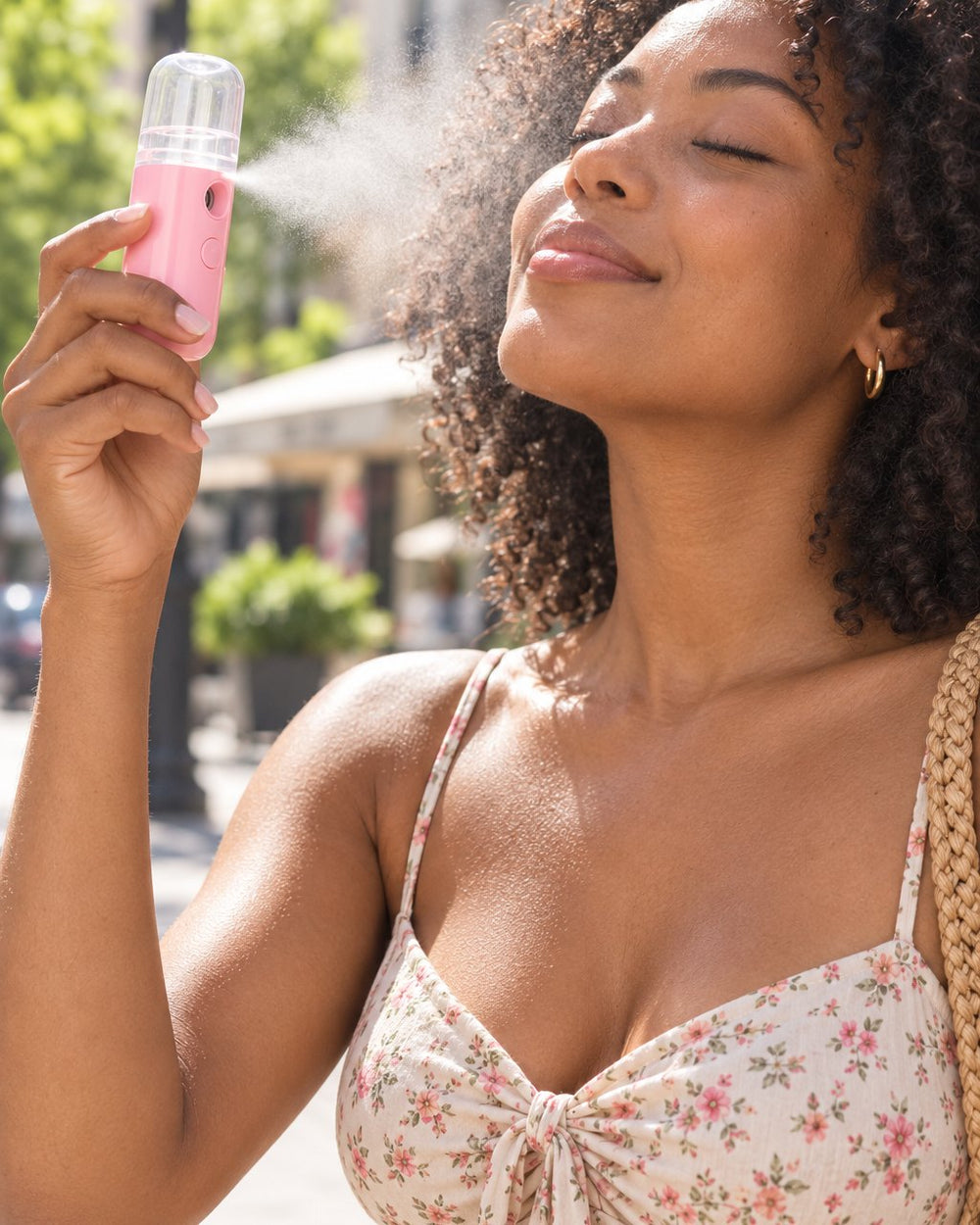 Woman misting her face with the pink nano mister on a sunny day