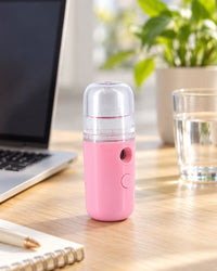 Nano mister on a desk beside a laptop and a glass of water