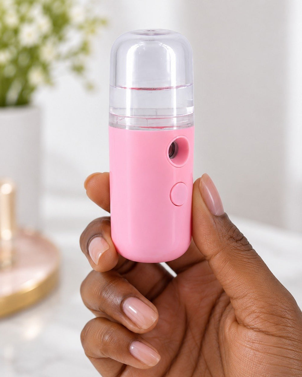 The nano mister held between fingers, about the size of a lipstick case