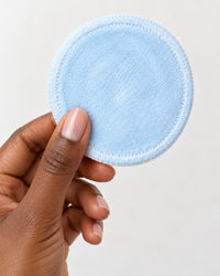 One reusable round held between fingers, a little bigger than a cotton pad