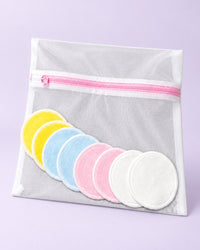 Eight soft reusable face rounds in four pastel colours beside a mesh wash bag