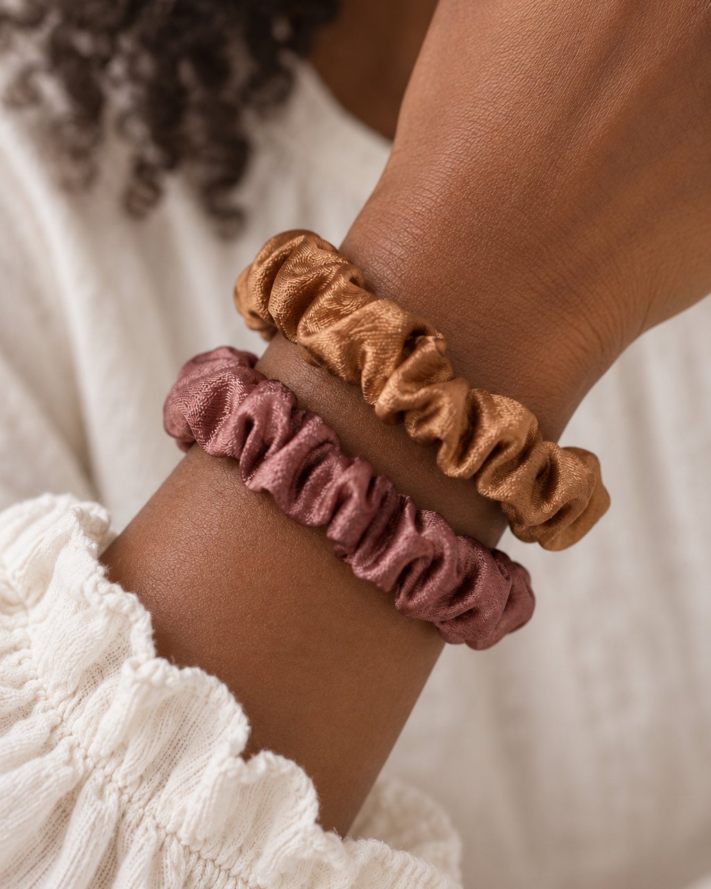 Two satin scrunchies worn on a wrist like bracelets