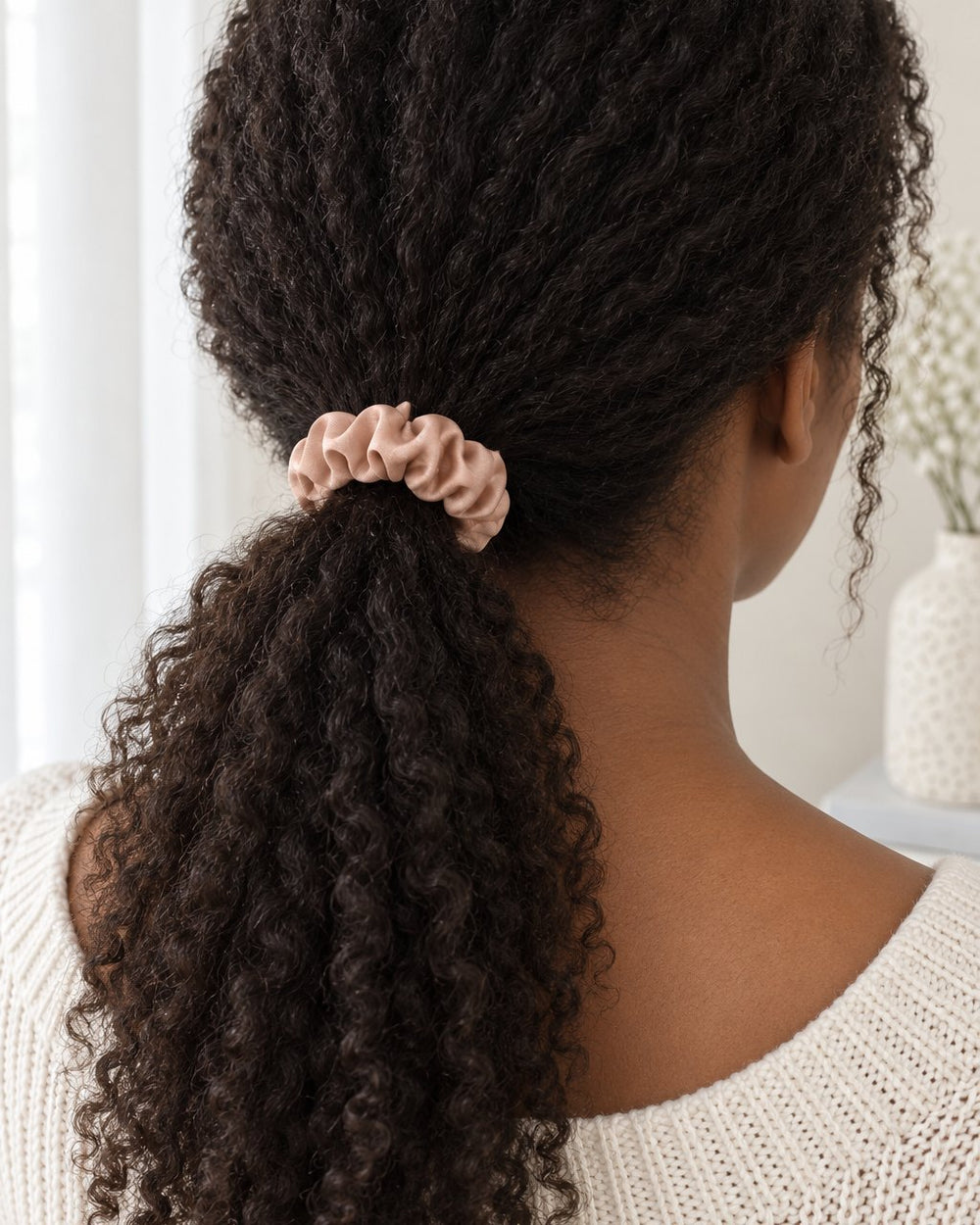 Woman's low ponytail tied with a blush satin scrunchie