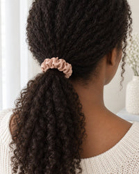 Woman's low ponytail tied with a blush satin scrunchie